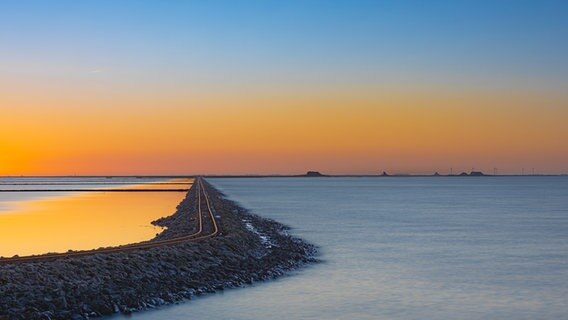 Ein Foto vom Meer, dieses wird durch eine aus Steinen aufgeschüttete Bahnstrecke geteilt. © Peter Kuhr Foto: Peter Kuhr