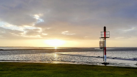 Die Sonne scheint am Abend bei bewölktem Himmel auf die Nordsee. © Anke Düwel Foto: Anke Düwel