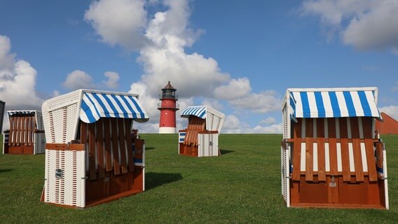 Strandkörbe stehen im Sonnenlicht mit einem Leuchtturm im Hintergrund. © Ingo von Oven Foto: Ingo von Oven