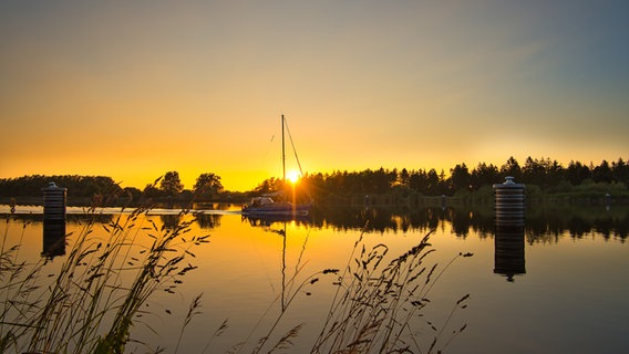 Ein Segelboot fährt auf dem Nord-Ostsee Kanal im Gegenlicht. © Ralf Horstmann Foto: Ralf Horstmann