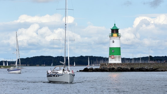 Ein Segelboot vor einem grün-weißen Leuchtturm in der Ostsee. © Hartwig Petersen Foto: Hartwig Petersen