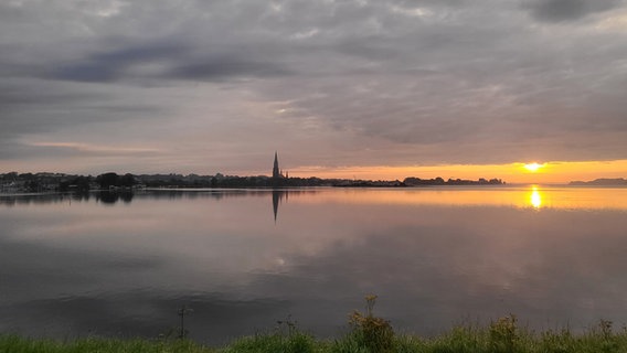 Sonnenaufgang über einem See mit Kirchturm. © Katja Albers Foto: Katja Albers