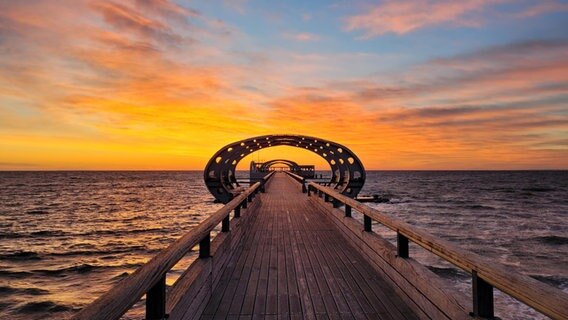 Auf der Seebrücke in Kellenhusen ist entlang des Stegs ein Sonnenaufgang in allen Farben zu bewundern. © Christian Storm Foto: Christian Storm