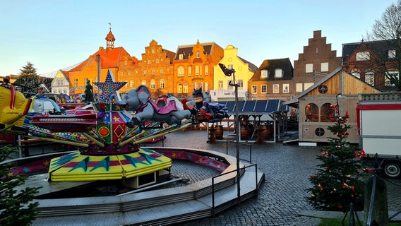 Ein Fahrgeschäft steht zwischen mehreren Weihnachtsmarkt-Buden auf einem Marktplatz. © Elisabeth Jaxa Foto: Elisabeth Jaxa