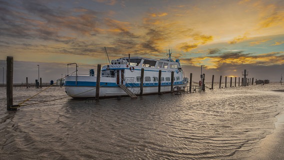 Ein Schiff liegt bei Sonnenuntergang im Hafen von Schlüttsiel. © Peter Kuhr Foto: Peter Kuhr