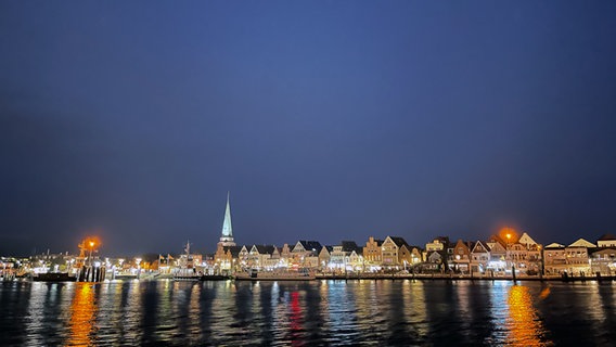 Eine Häuserreihe von Travemünde spiegelt sich in der Nacht mit den Lichtern im Wasser der Ostsee. © Simona Tietze Foto: Simona Tietze