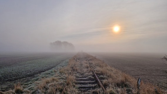 Bedeckter Himmel über einem Feld mit einer stillgelegten Bahnstrecke. © Sibylle Deertz Foto: Sibylle Deertz
