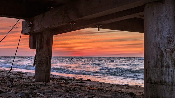 Sonnenuntergang am Strand von Heiligenhafen. Fotografiert unter einem Steg. © Stefan Hell Foto: Stefan Hell