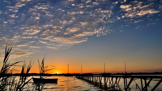 Ein Boot treibt bei Sonnenuntergang am Ufer der Schlei in Büstorf bei Rieseby. © Rüdiger Seemann Foto: Rüdiger Seemann