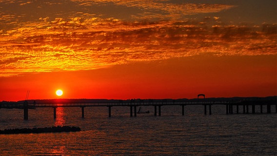 Ein Sonnenuntergang vor einem Steg, der den Himmel rot färbt. © Hans-Otto Klies Foto: Hans-Otto Klies