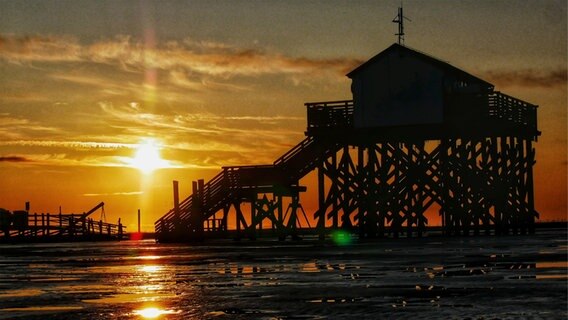 Ein Sonnenaufgang vor den Pfahlbauten am Böhler Strand. © Achim Otto Foto: Achim Otto