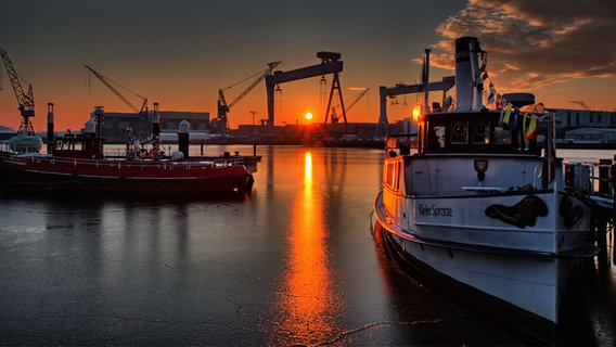 Die Sonne geht am Kieler Hafen zwischen den HDW-Kränen auf. © Frank Kleinert Foto: Frank Kleinert