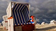 Dunkle Wolken über dem Strandkorb in St. Peter-Ording. © Achim Otto Foto: Achim Otto