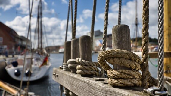 Ein Stillleben des Neustaädter Hafens. Im Vordergrund sieht man ein Bootstau, dahinter ein Segelboot und den Hafen. © Ralf-Georg Janke Foto: Ralf-Georg Janke
