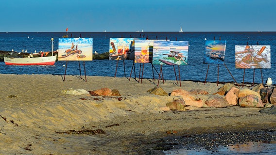 Sechs Gemälde stehen vor dem Meer auf dem Strandabschnitt bei Sierksdorf. © Anja Krellenberg Foto: Anja Krellenberg