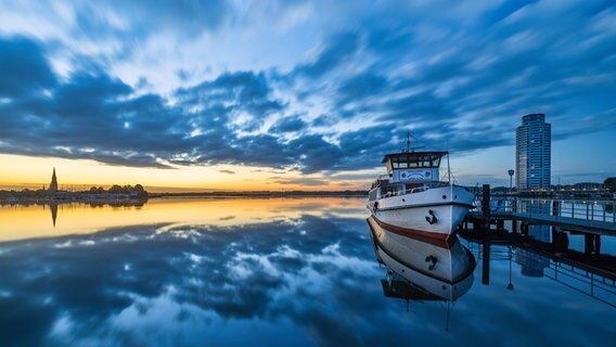 Ein Boot liegt auf der Schlei während die Sonne aufgeht. © Bodo Puttins Foto: Bodo Puttins