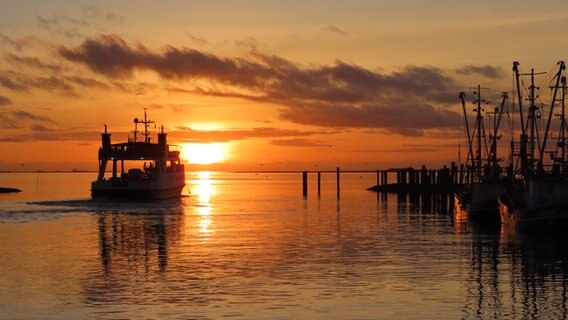 Die Sonne geht hinter der ausfahrenden Fähre im Meer unter.  Foto: Ulrike Bahnsen