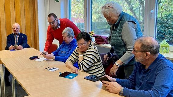 Eine Gruppe Senioren lernt den Umgang mit einem Smartphone. © NDR Foto: Andrea Schmidt