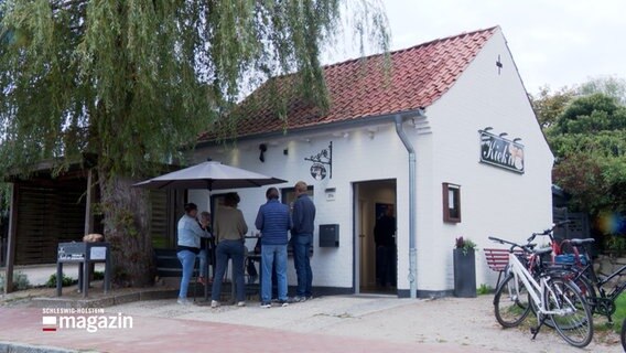 Mehrere Personen stehen vor einem Kiosk und trinken Kaffee. © NDR Foto: NDR Screenshots