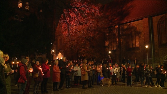 Eine Menschenmenge steht mit Kerzen vor einer Kirche. © NDR 
