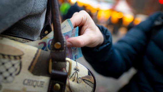 Eine Person stiehlt Geld aus einer Tasche. © IMAGO / Agentur 54 Grad 