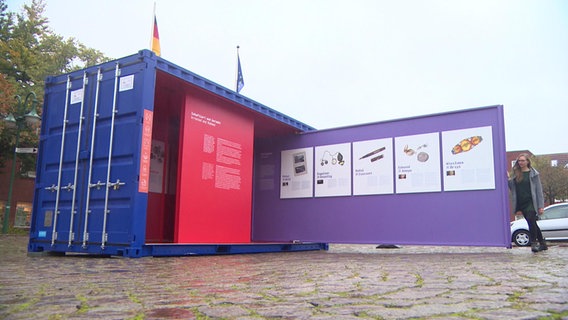 Ein Container der Ausstellung "Stolen Memory" steht auf einem Marktplatz. © Screenshot 