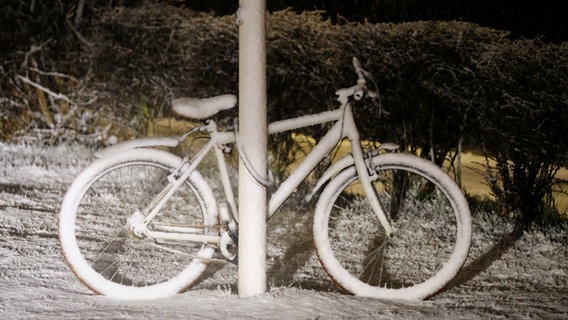 Ein verschneites Fahrrad steht an einer Straßenlaterne. © Sebastian Iwersen Foto: Sebastian Iwersen