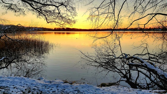 Ein See beim Sonnenuntergang und Schnee bedeckte Bäume. © Diederik Thaler Foto: Diederik Thaler