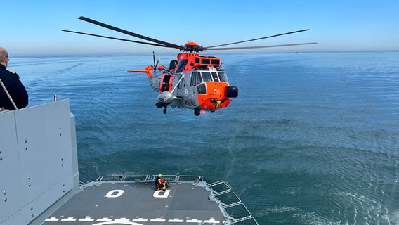 Ein hubschrauber der Marine schwebt über dem Heck eines Marine-Schiffes. © Michael van Engelen Foto: Michael van Engelen