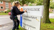 Ein Mann klebt den Schriftzug "Schön Klinik" auf ein Schild in Rendsburg © Schön Klinik 