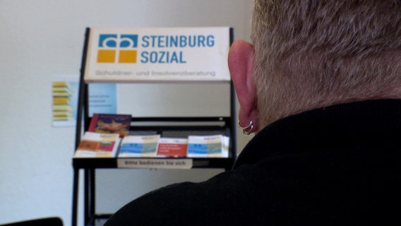 Ein Mann sitzt in einem Raum bei der diakonischen Schuldnerberatung in Steinburg. © NDR 