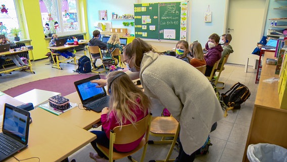 Eine Lehrerin zeigt einer Grundschülerin etwas auf einem Laptopbildschirm in Oelixdorf. © NDR 