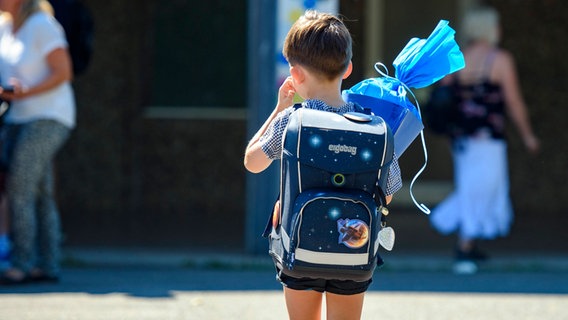 Ein Junge mit blauem Ranzen und Schultüte auf einem Schulhof. © Imago Images Foto: Kirchner-Media