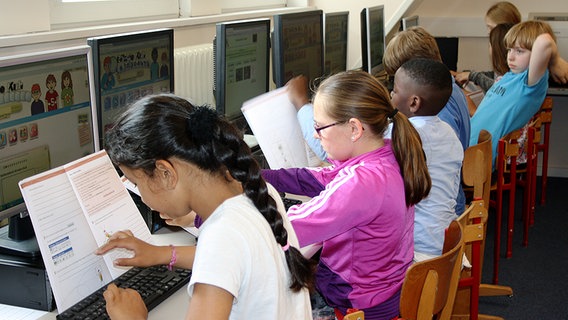 Schüler sitzen mit ihrem Lernmaterial vor Computern. © NDR Foto: Simone Steinhardt