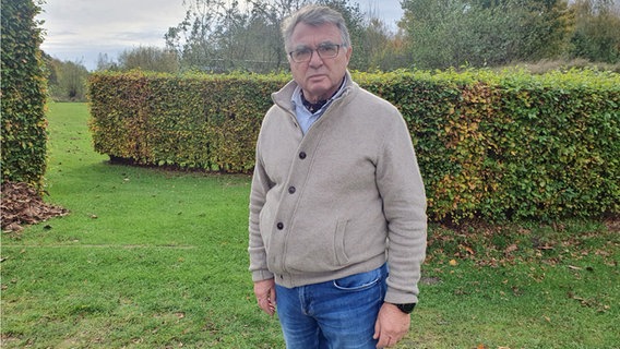 Werner Schweizer, Bürgermeister von Klixbüll, steht in einem Garten. Werner Schweizer, Bürgermeister von Klixbüll, steht in einem Garten. © NDR Info Foto: Nadja Mitzkat