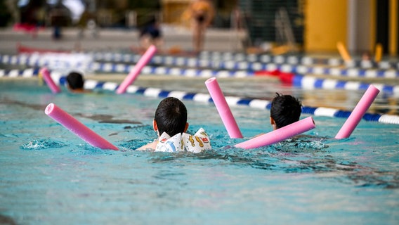 Kinder schwimmen mit Schwimmhilfen in einem Hallenbad. © picture alliance/dpa | Jens Kalaene Foto: Jens Kalaene