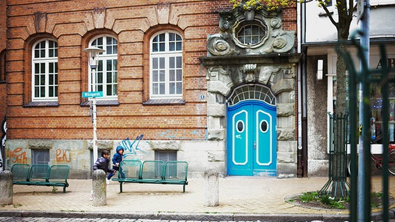 Außenansicht des Gebäudes der Jüdischen Gemeinde Kiel und Region e.V. mit einer hellblauen Tür. Zwei Kinder laufen vorbei. © NDR Foto: Lisa Pandelaki