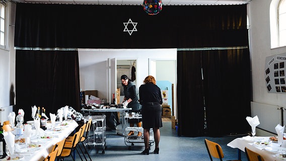 Zwei Frauen bereiten den Sederabend in der Synagoge vor und decken die Tische ein. © NDR Foto: Lisa Pandelaki