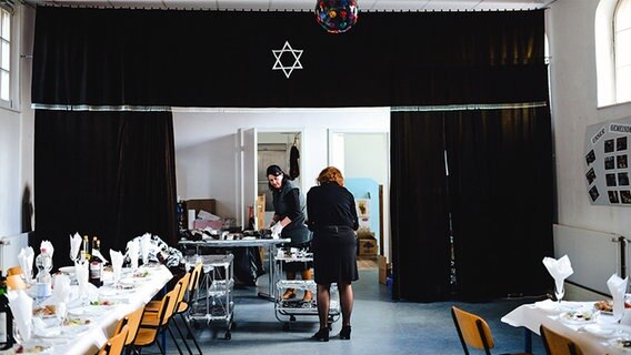 Zwei Frauen bereiten den Sederabend in der Synagoge vor und decken die Tische ein. © NDR Foto: Lisa Pandelaki