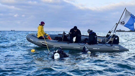 Ein Boot liegt im Wasser, vor ihm sind zwei Taucher im Wasser. © NDR Foto: Jörn Zahlmann