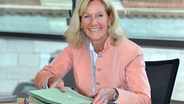 Gaby Schäfer, Präsidentin des Landesrechnungshofs sitzt im Plenarsaal des Landtages in Kiel und lächelt in die Kamera. © Landesrechnungshof Schleswig-Holstein 