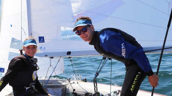 Anastasiya Winkel und ihr Ehemann lächeln auf ihrem Boot zur Kamera. © NDR Foto: Marina Heller