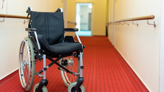 Ein leerer Rollstuhl steht auf dem Gang eines Seniorenheimes. © imago images / Fotostand Foto: Fotostand