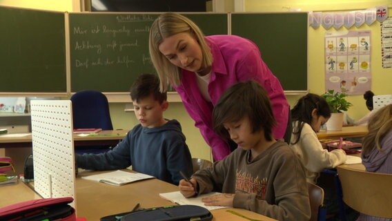 Eine Person erklärt Schülern in einer Schule den Schulstoff an einem Gruppentisch Eine Person erklärt Schülern in einer Schule den Schulstoff an einem Gruppentisch © NDR Foto: NDR Screenshot