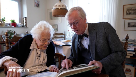 Gisela Brinkmann und Max Manke sitzen in einem Wohnzimmer und schauen in ein Fotoalbum © NDR 