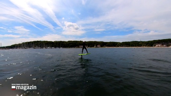 Eine Person surft auf einem sogenannten e-Foil auf dem Wasser. © NDR Screenshots Foto: NDR