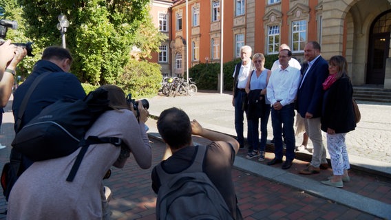 Menschen werden vor einem Gerichtsgebäude fotografiert. © NDR Foto: NDR Screenshots