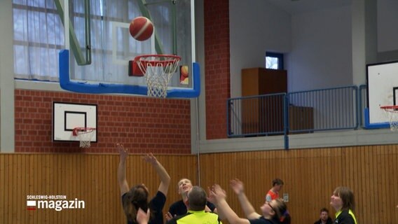 Mehrere Sportler betrachten einen Basketball bei einem Wurf auf den Korb. © NDR Foto: NDR Screenshot