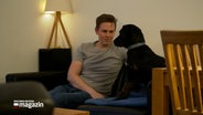Ein Mann mit einem Hund auf einem Sofa © NDR Foto: NDR Screenshot