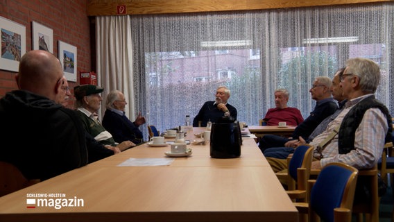 Mehrere Männer sitzen an einem Tisch und diskutieren © NDR Foto: NDR Screenshot